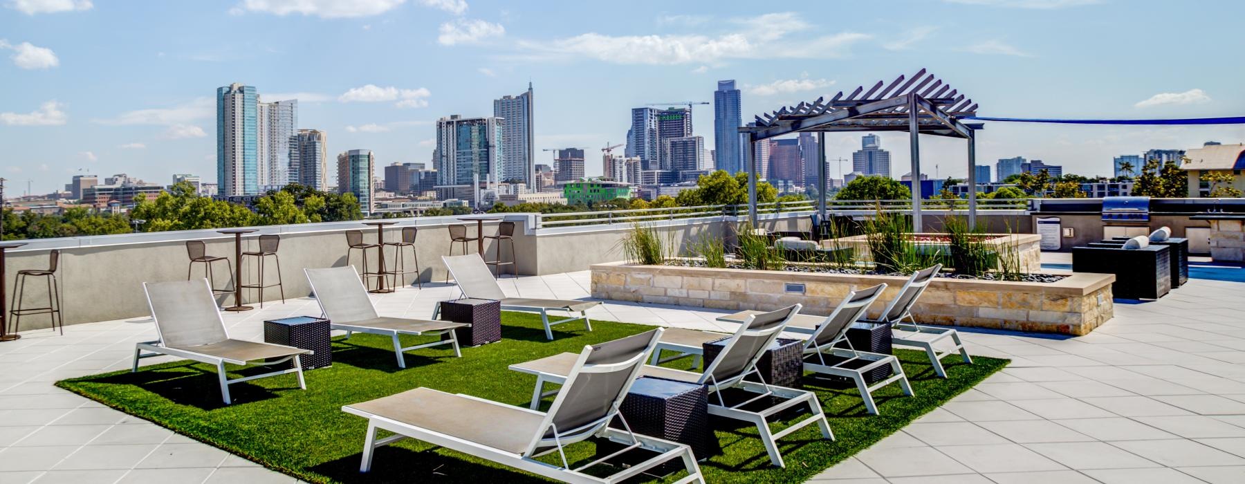 a patio with chairs and tables and a city skyline in the background