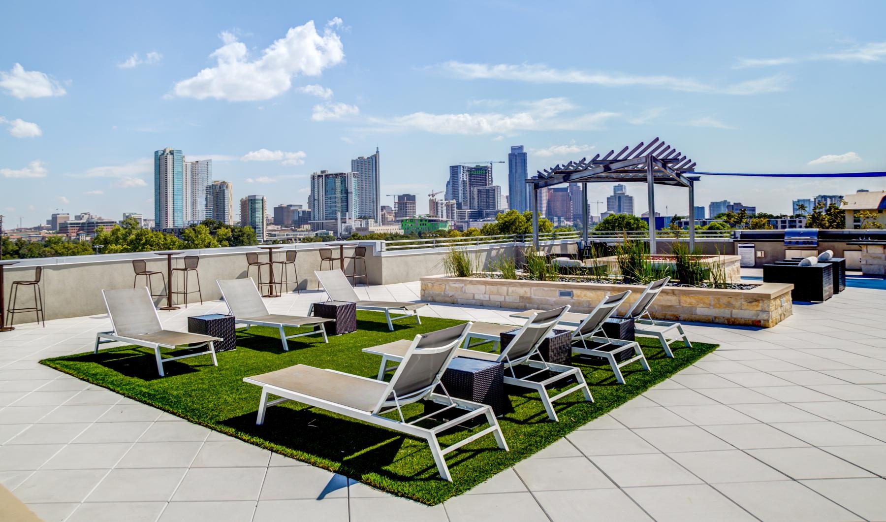 a patio with chairs and tables and a city skyline in the background